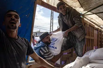 Penduduk Palestin menerima tepung yang diagihkan oleh Agensi Bantuan dan Kerja Menyelamat Pertubuhan Bangsa-Bangsa Bersatu (PBB) bagi Pelarian Palestin (UNRWA) di pusat pengagihan di Khan Younis, selatan Jaluran Gaza pada 31 Oktober.