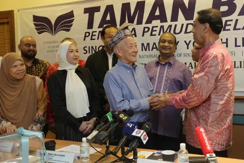 SAMBUT BAIK: Encik Ng Kok Song kelihatan menerima hadiah tanjak daripada Presiden Taman Bacaan, Encik Abdul Halim Kader ketika lawatannya di Taman Bacaan di Jalan Damai pada petang Rabu.