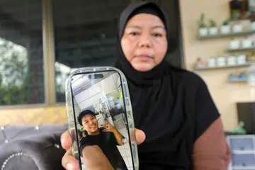 KASIH IBU: Cik Mimi Julia Ismail, ibu Allahyarham Muhammad Zaharif Affendi Muhd Zamrie, 17 tahun, yang maut selepas dilanggar pegawai kanan polis ketika menaiki motosikal pulang ke rumah selepas tamat waktu sekolah pada 15 Disember lalu, menunjukkan gambar anaknya itu yang menjadi tatapan melepas rindu. 