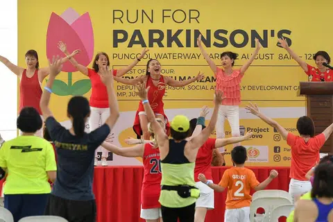 BERSENAM DAHULU: Peserta diajak melakukan senaman ringkas zumba sebelum memulakan larian amal di Taman Waterway Punggol semalam. - Foto BH oleh LIM YAOHUI