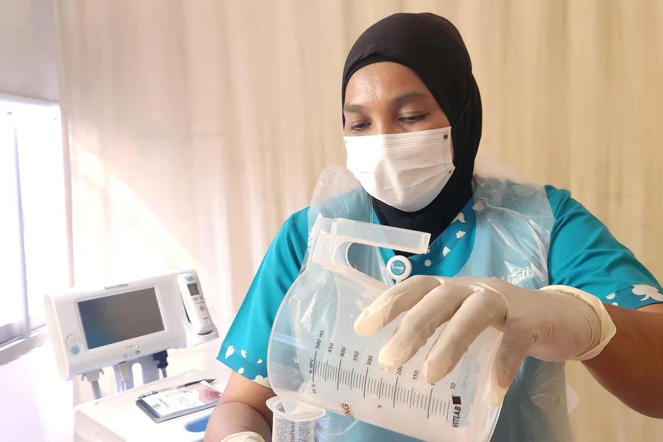 TUGASAN HARIAN: Cik Siti Fatimah Mustaffa kelihatan memberikan Pemakanan Tiub Nasogastrik (NGT feeding) dan mengambil ukuran tanda vital antaranya mengambil ukuran tekanan darah pesakit. 