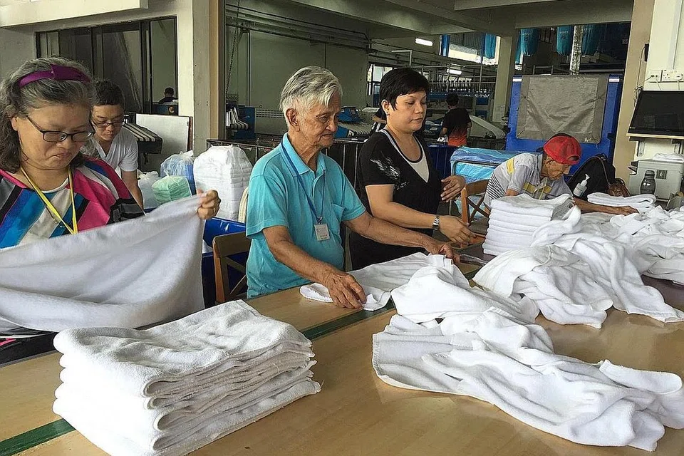 BERSYUKUR: Encik Mustafa (tengah, berkemeja-T hijau muda) gembira bantuan Yayasan Harapan CapitaLand (CHF) dapat menceriakan penduduk Apex Harmony Lodge sepertinya semasa tempoh pemutus rantaian jangkitan. Sebelum koronavirus Covid-19 melanda, beliau dan beberapa penghuni rumah tumpangan itu menyertai sesi terapi kerja di Orchid Laundry dengan melipat tuala dua kali seminggu dan diberi elaun kecil (gambar atas). Tetapi sejak penguatkuasaan tempoh pemutus rantaian jangkitan, beliau tidak lagi dapat menyertai sesi tersebut. - Foto APEX HARMONY LODGE