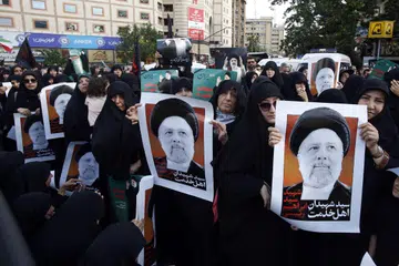 Penduduk wanita Iran dilihat memegang poster Presiden Iran, Encik Ebrahim Raisi, di upacara berkabung di Teheran pada 20 Mei. 