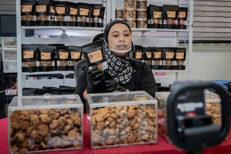 BERINTERAKSI DENGAN PELANGGAN: Cik Nur Atiqah akan membungkus pesanan biskut semasa TikTok ‘live’ yang diadakan satu hari dalam seminggu, pada waktu malam. 