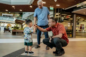Anggota Parlimen (AP) GRC Marine Parade, Encik Fahmi Aliman (kanan), berinteraksi dengan seorang kanak-kanak semasa bertemu penduduk di Wisma Geylang Serai. 