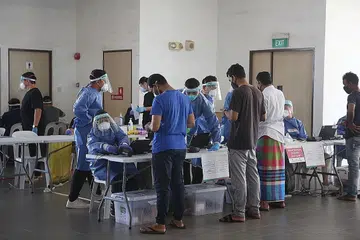 TANGKAS BERTINDAK: Pekerja asing di sebuah dormitori di Tuas dibantu menjalani ujian Covid-19. Agensi awam tangkas dalam beralih daripada peranan sebelum pandemik kepada peranan kecemasan baru yang menyaksikan mereka meningkatkan operasi dengan ketara dan pantas semasa pandemik Covid-19 melanda, kata Kementerian Kewangan (MOF). - Foto fail