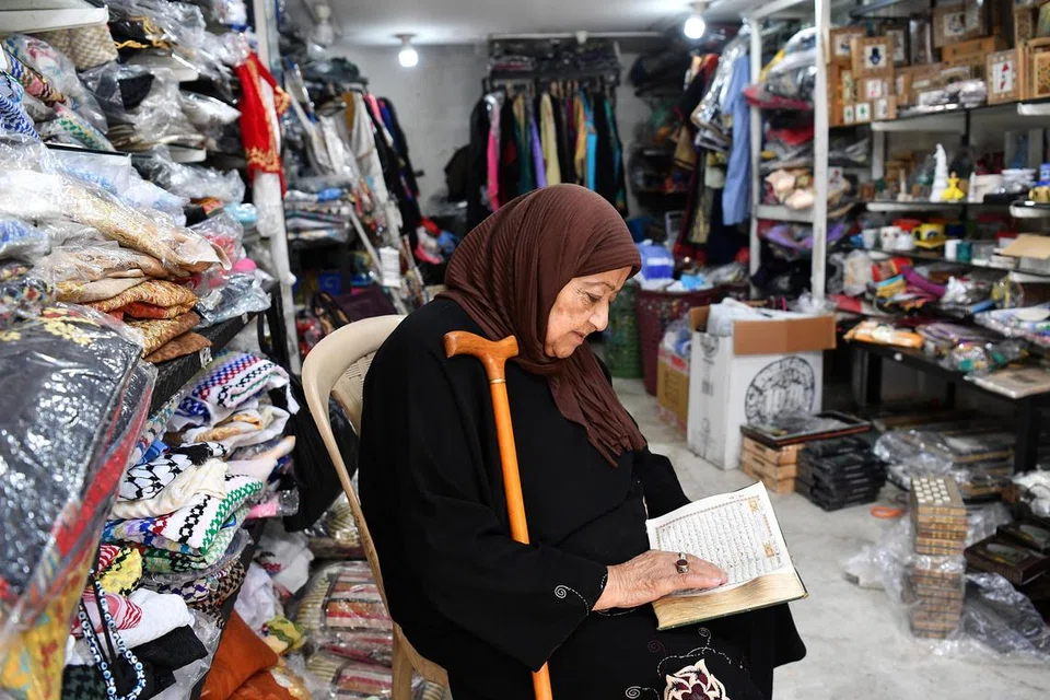 MENUNGGU PELANGGAN: Seorang peniaga di sebuah bazar di Beirut, Lebanon menghabiskan masa membaca Al-Quran sementara menunggu pelanggan dalam suasana sepi menjelang Aidiladha