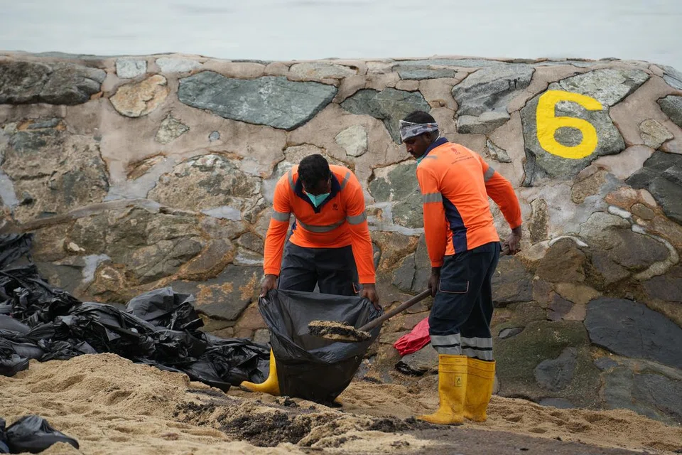 Beberapa pekerja dilihat mencangkul pasir yang tercemar ke dalam beg sampah untuk dibuang pada 16 Jun di pantai East Coast Park.