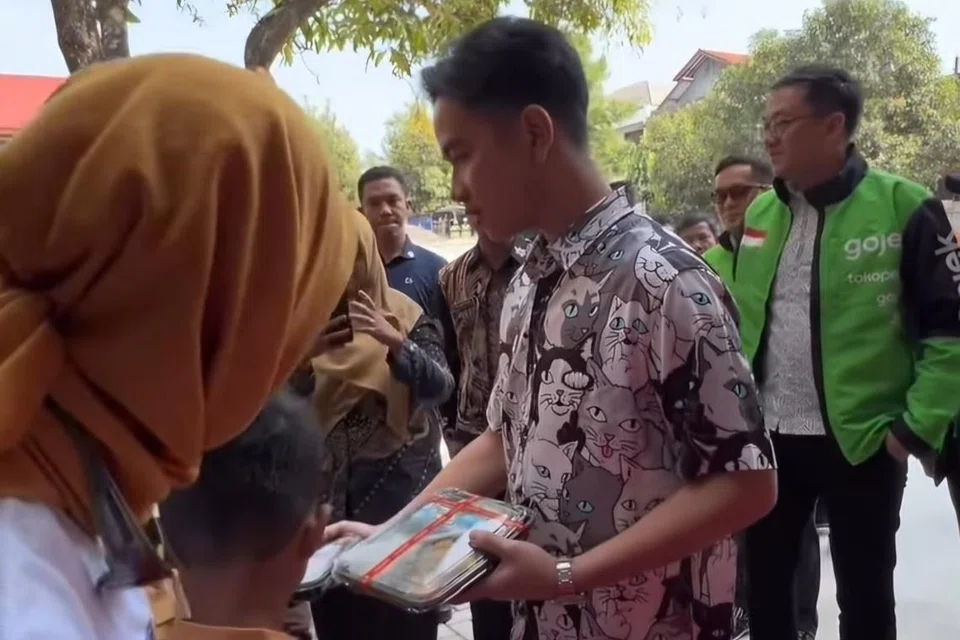 Bakal Naib Presiden, Encik Gibran Rakabuming Raka, membahagikan makanan percuma kepada pelajar sekolah sedang Indonesia akan melancarkan ribuan dapur di seluruh negara bermula 2025.