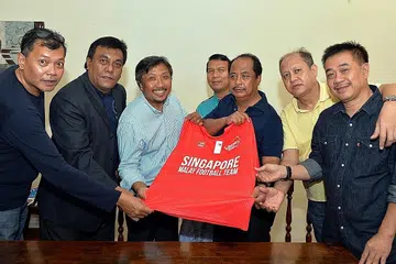 SAHUT CABARAN: Pengerusi Pasukan Bola Sepak Melayu Singapura (SMFT), Muhammad Zaki Ma'arof (tiga dari kiri), menghulurkan cenderahati kepada presiden Persatuan Bola Sepak Melayu Malaysia (PBSMM), Dato' Sri Wan Adnan Wan Mamat (tiga dari kanan), dalam pertemuan muhibah di sini minggu lalu. Bersama dalam gambar ialah pegawai utama kededua persatuan itu (dari kiri) timbalan ketua SMFT, Salman Abdullah; pengurus skuad Melayu Singapura, Shahri Rahim; timbalan ketua kedua SMFT, Razali Rashid; naib presiden PBSMM, Datuk Ramlan Askolani; dan di belakang ialah anggota majlis PBSMM, Mohd Zamri Mazleh. - Foto ZAINAL YAHYA