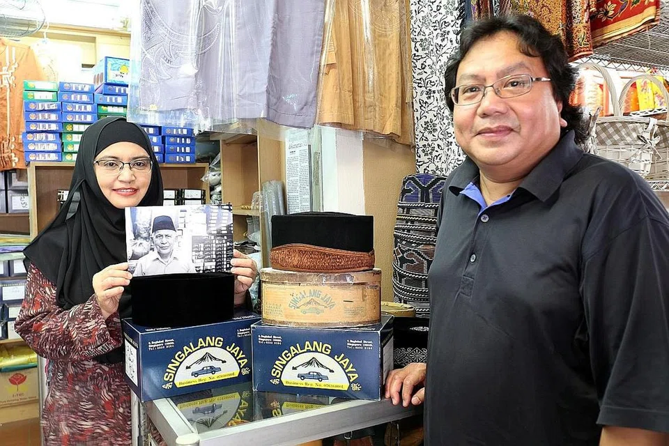 TERUSKAN WARISAN BAPA: Cik Isneli (kiri), sambil memegang gambar Allahyarham Haji Baharuddin Sulaiman, pemilik asal kedai songkok Singalang Jaya, berharap dapat meneruskan perniagaan bapanya itu. Bersamanya ialah suami, Encik Hashmy, yang pernah membantu arwah mengendalikan kedai itu dahulu. - Foto FAKHRURADZI ISMAIL