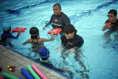 LEBIH RAMAI TERTARIK: Jurulatih renang, Cik Zafirah Idris (tengah), dengan kanak-kanak yang menyertai kelas renang Swim Schooling di Our Tampines Hub (OTH). Ramai kanak-kanak, katanya, terdorong mempelajari kegiatan renang itu kerana tertarik dengan pencapaian jaguh renang negara di Sukan Olimpik, Joseph Schooling. - Foto ARIFFIN JAMAR