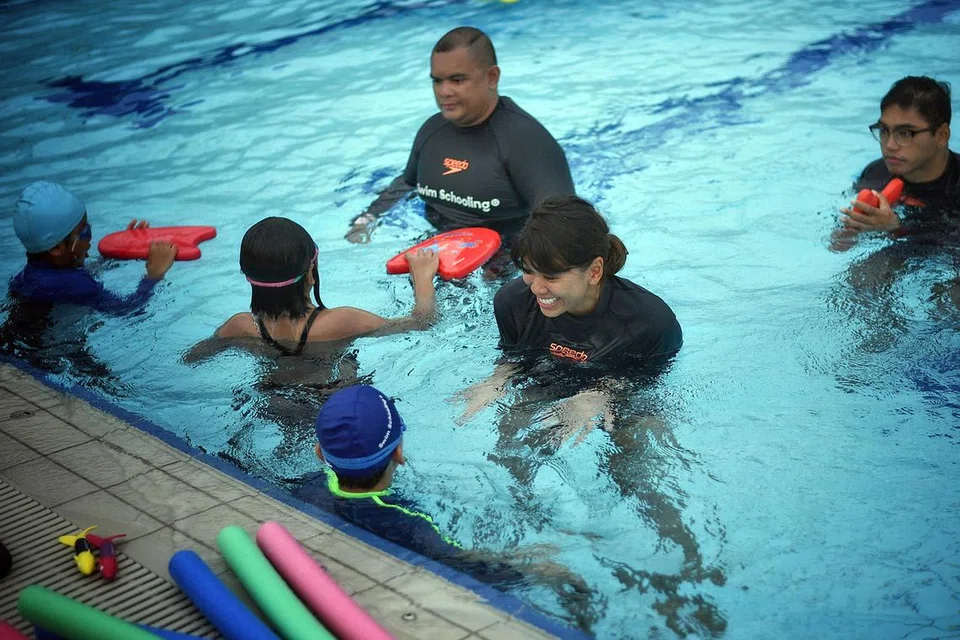LEBIH RAMAI TERTARIK: Jurulatih renang, Cik Zafirah Idris (tengah), dengan kanak-kanak yang menyertai kelas renang Swim Schooling di Our Tampines Hub (OTH). Ramai kanak-kanak, katanya, terdorong mempelajari kegiatan renang itu kerana tertarik dengan pencapaian jaguh renang negara di Sukan Olimpik, Joseph Schooling. - Foto ARIFFIN JAMAR