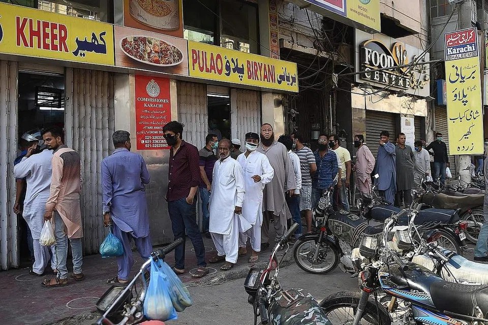 BAWA RISIKO: Penduduk Muslim beratur untuk membeli makanan berbuka puasa di Karachi, Pakistan. - Foto AFP