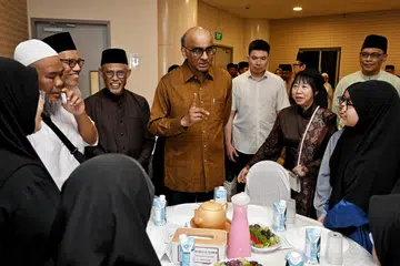 Presiden Tharman Shanmugaratnam (lima dari kiri), bersama isterinya, Puan Jane Ittogi (tiga dari kanan), dan Menteri Bertanggungjawab bagi Ehwal Masyarakat Islam, Encik Masagos Zulkifli Masagos Mohamad (empat dari kiri) bersama beberapa jemaah yang menghadiri acara berbuka puasa di Masjid Maarof pada 9 Mac. 