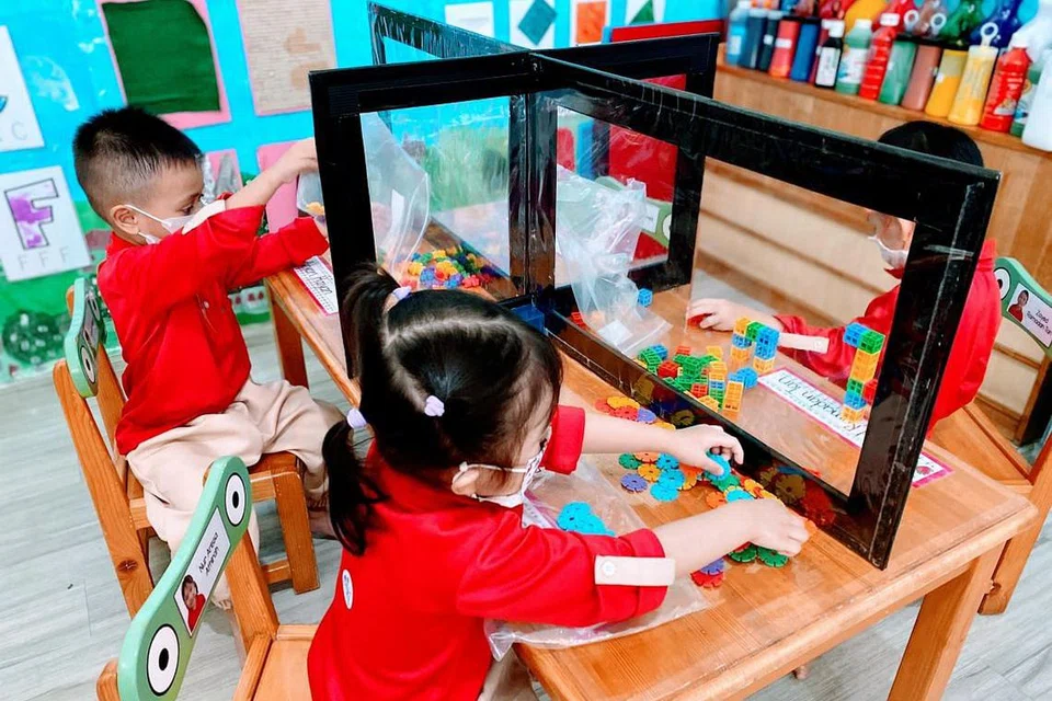 BERMAIN DENGAN SELAMAT: Murid di tajaka Ilham Child Care bermain di meja mereka yang dipasang dengan pelindung, dalam langkah selamat diperketatkan. - Foto ILHAM CHILD CARE 