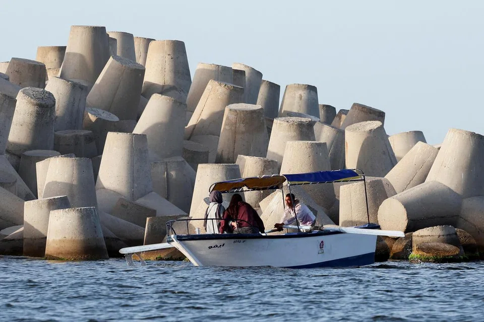 Beberapa orang menaiki bot melepasi penghadang konkrit yang baru dibina di bandar Mediterranean Iskandariah, Mesir, pada 20 April 2025. 