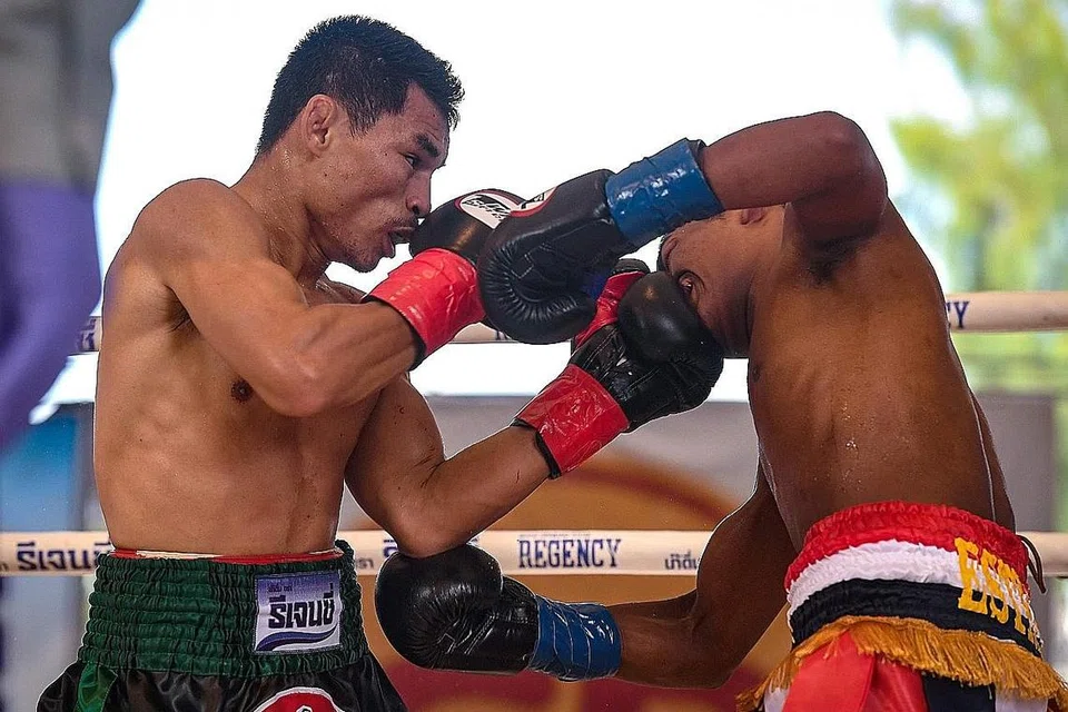 TUMBUKAN KENCANG: Jaguh Thai, Wanheng Menayothin (kiri), membelasah pencabarnya dari Panama, Leroy Estrada, untuk meneruskan rekod cemerlangnya kepada 50 kemenangan berturut-turut. - Foto AFP 