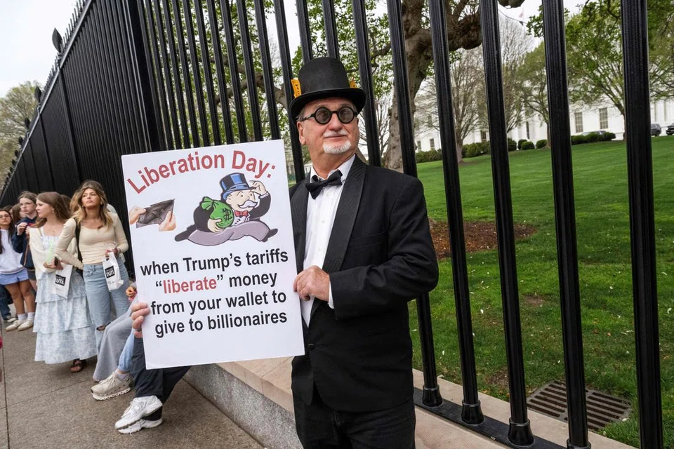 Seorang penduduk Washington berusia 71 tahun yang memperkenalkan dirinya sebagai Daddy Warlocks memegang sepanduk sebagai tanda protes terhadap dasar tarif ekonomi yang dikenakan oleh Presiden Amerika Syarikat, Donald Trump, di luar Rumah Putih di Washington, DC, pada 2 April 2025.