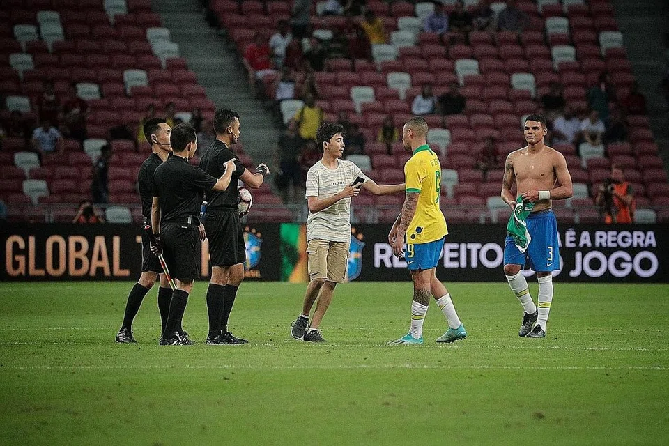 AMBIL KESEMPATAN: Seorang peminat muda cuba mengambil kesempatan bergambar dengan penyerang Brazil, Gabriel Jesus (jersi kuning), selepas dia mencerobohi padang di Stadium Negara ketika perlawanan antara Brazil dengan Senegal pada 10 Oktober lalu. - Foto BH oleh JASON QUAH