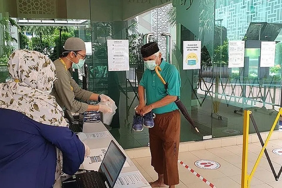 PAKAI PELITUP: Pengunjung di Masjid Muhajirin (baju hijau) ini memakai pelitup dan membawa masuk selipar sendiri semasa mendaftar di sistem Safe Entry. Jemaah diminta membawa kad pengenalan bagi pendaftaran dan membawa peralatan solat peribadi. - Foto FACEBOOK MUHAJIRIN