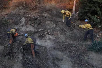 Pasukan bomba membersihkan sampah sarap dan mematikan bara api sebagai langkah mencegah kebakaran daripada berulang akibat angin Santa Ana yang kembali bertiup di selatan California.