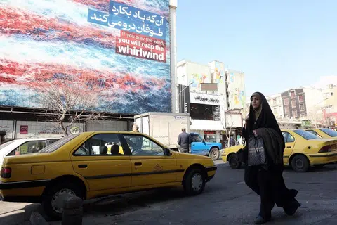 Seorang wanita Iran berjalan melepasi papan iklan anti-Amerika Syarikat di Tehran, Iran, 25 Februari 2026. Amerika Syarikat dan Iran dijadual menyambung pusingan ketiga rundingan nuklear penting di Geneva.