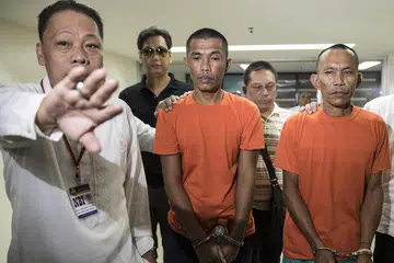 DIBERKAS: Anggota militan Hood Abdullah (tengah, berbaju jingga) dan Jimmy Bla (kanan) diiring sebelum sidang akhbar di Manila semalam. - Foto AFP