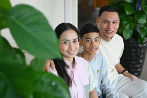 Cik Izlin Ismail dan Encik Mohamed Huzaini bersama anak mereka, Hayden Anash, di Menara NUHS pada 26 Jun 2025. Hayden, pernah dikejarkan ke hospital ketika berusia tiga bulan selepas mengalami bengkak akibat minum susu tepung. Dia kemudian disahkan mengalami alahan terhadap susu, telur dan kacang tanah. Kini, Hayden menyertai kajian yang meneliti kesan alahan makanan terhadap kanak-kanak di Singapura.