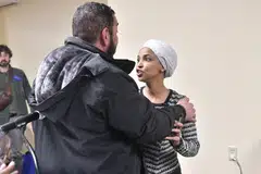 Wakil Rakyat Amerika Syarikat, Ilhan Omar (Demokrat–Minnesota) (kanan), bertindak balas selepas disembur bahan yang tidak dikenal pasti oleh seorang lelaki ketika beliau menganjurkan sesi town hall di Minneapolis, Minnesota, pada 27 Januari 2026.