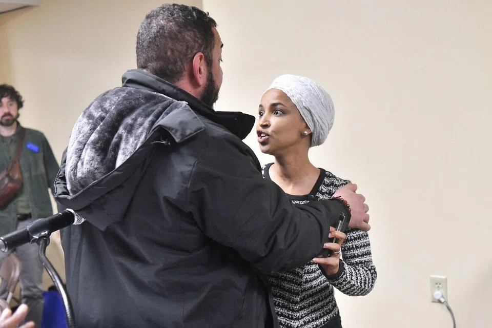 Wakil Rakyat Amerika Syarikat, Ilhan Omar (Demokrat–Minnesota) (kanan), bertindak balas selepas disembur bahan yang tidak dikenal pasti oleh seorang lelaki ketika beliau menganjurkan sesi town hall di Minneapolis, Minnesota, pada 27 Januari 2026.