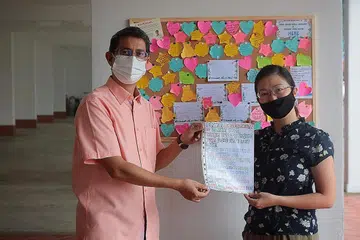 PUPUK SIFAT PERPADUAN: Dr Muhammad Faishal Ibrahim bersama pencetus inisiatif "Papan Notis Terima Kasih", Cik Jaslyne Chia, di Blok 745 Yishun Street 72. - Foto BH oleh JASON QUAH