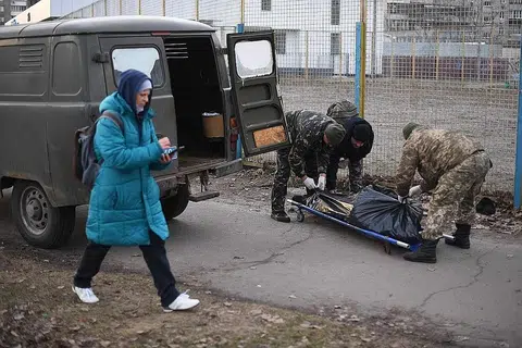 PETAKA PERANG: Seorang wanita berjalan melepasi dua askar Ukraine yang sedang mengangkat mayat warganya yang menjadi mangsa serangan tentera Russia di utara Kyiv, kelmarin. Presiden Ukraine, Encik Volodymyr Zelensky, berkata tentera Russia menyasarkan orang awam dan ledakan bom boleh didengar di ibu kota yang telah dikepung itu. - Foto AFP