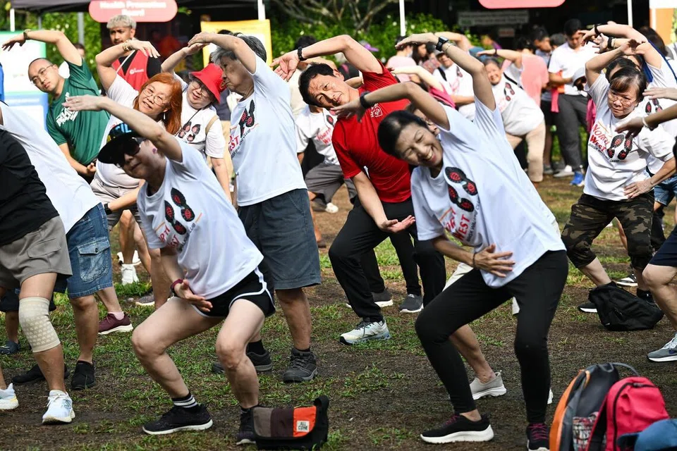 Menteri Kesihatan, Encik Ong Ye Kung (berbaju merah), menyertai aktiviti senaman beramai-ramai di pelancaran gerakan berjalan pantas baru di Sembawang Central pada 12 April.