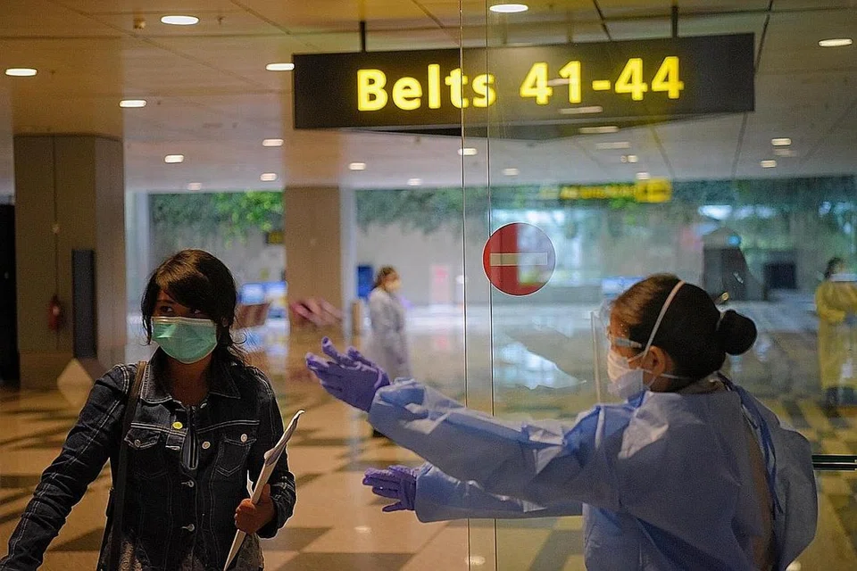 LANGKAH DIPERKETAT: Kakitangan lapangan terbang di Terminal 3 mengawal pergerakan penumpang sambil memakai Peralatan Perlindungan Peribadi (PPE). Ini menyusuli protokol yang dipertingkat bagi pekerja yang bertugas di kawasan berisiko tinggi yang membabitkan interaksi bersama pelawat yang tiba di sini. - Foto BH oleh MARK CHEONG.