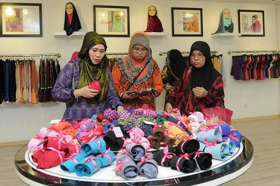 PRODUK BARU: Cik Lynn (kiri) menunjukkan beberapa produk baru Tudungku kepada pelanggan di butik terbarunya dalam kawasan Tampoi, Johor Bahru. - Foto THEME PHOTOGRAPHY