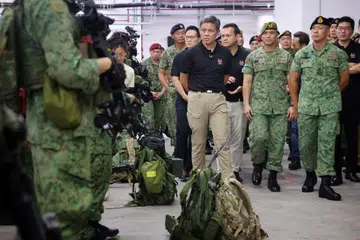 Menteri Pertahanan, Encik Chan Chun Sing (baju hitam, tengah) yang diiringi Menteri Negara Kanan (Pertahanan), Encik Zaqy Mohamad (baju hitam, kanan), dan Menteri Negara (Pertahanan), Encik Desmond Choo (baju hitam, kiri), menemui Pasukan Pengerahan Tentera Darat (ADF) di Kem Nee Soon.