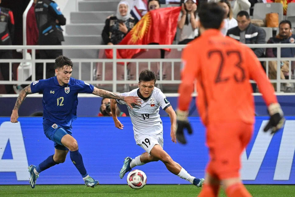 LICIK DAN LINCAH: Beknaz Almazbekov (jersi putih) membawa lari bola daripada pemain Thailand, Look Saa Mickelson dalam perlawanan Kumpulan F antara Kyrgyzstan danThailand di Stadium Abdullah bin Khalifa di Doha. Thailand menang perlawanan itu 2-0. 