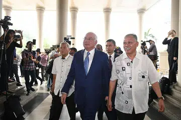 PERBICARAAN BERMULA: Datuk Najib (depan,kiri) tiba di Mahkamah Tinggi di Kuala Lumpur semalam, bagi menghadiri perbicaraan kes 1MDB, di mana beliau dituduh menyeleweng ratusan juta dolar. Kes itu akan dihadapkan lagi ke mahkamah hari ini. - Foto AFP