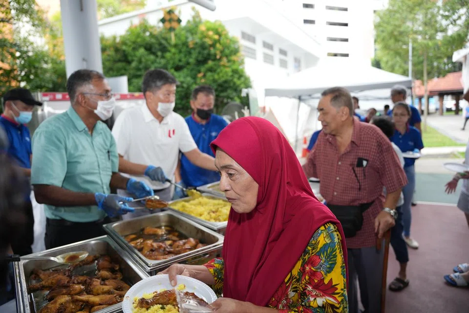 (Dari kiri) Penasihat Pertubuhan Akar Umbi (GRO) Bukit Batok, Encik Murali Pillai dan Setiausaha Agung Kongres Kesatuan Sekerja Kebangsaan, Encik Ng Chee Meng, menghidangkan makanan kepada Encik Senin Ahmad (berbaju merah) dan isteri sempena acara ‘Block Party’ anjuran FairPrice Group pada 20 April.