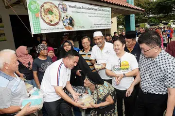 AGIH BERIANI: Encik Amrin mengagih nasi beriani yang disiapkan oleh Masjid Khalid kepada penduduk kawasan Woodlands sebelum waktu berbuka. Turut serta ialah pengerusi Masjid Khalid, Haji Allaudin Mohamed (bersongkok putih). - Foto JOHARI RAHMAT