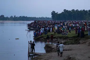 Orang ramai berkumpul di sepanjang tebing sungai Karatoya selepas sebuah bot karam berhampiran bandar Boda. 