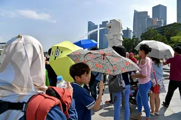 CUACA PANAS: Pengunjung ke Taman Merlion menggunakan payung dan botol air bagi menghadapi cuaca panas bulan lalu.