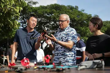 LEBIH SELESA: Encik Iswaran (tengah) sempat melihat salah sebuah dron semasa di kawasan lapang dekat Takungan Air Pandan yang lebih luas dan selesa untuk para penggemar kegiatan tersebut. - Foto BH oleh GIN TAY