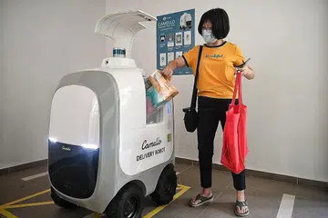 ROBOT GERAK SENDIRI BUAT PENGHANTARAN: Gambar menunjukkan demonstrasi penghantaran barang-barang oleh robot gerak sendiri yang dilancarkan semalam di Blok 667A Waterway WoodCress, Punggol. Cik Christine Chong, 53 tahun, menerima barangannya melalui robot tersebut. - Foto BH oleh KUA CHEE SIONG
