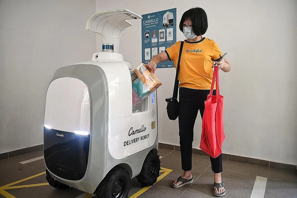ROBOT GERAK SENDIRI BUAT PENGHANTARAN: Gambar menunjukkan demonstrasi penghantaran barang-barang oleh robot gerak sendiri yang dilancarkan semalam di Blok 667A Waterway WoodCress, Punggol. Cik Christine Chong, 53 tahun, menerima barangannya melalui robot tersebut. - Foto BH oleh KUA CHEE SIONG