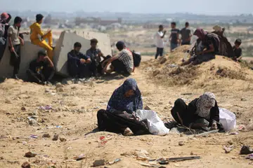 Wanita Palestin mencari kekacang dan beras di celah pasir di Nuseirat, Gaza tengah, ketika misi bantuan udara dijalankan di wilayah Palestin yang dikepung Israel pada 5 Ogos 2025.