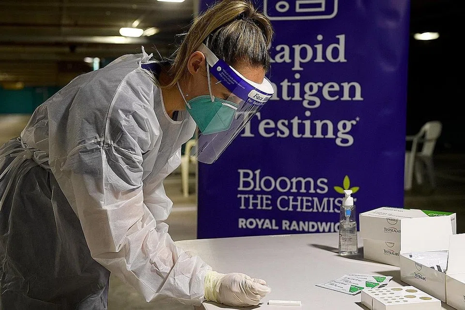TARIK BALIK: Jururawat, Cik Niamh Costello, menunjukkan cara menjalankan Ujian Pantas Antigen Covid-19 di kemudahan pandu lalu di premis Blooms the Chemist di Sydney, Australia. - Foto EPA-EFE