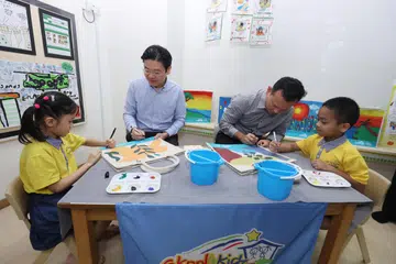 SUMBANG KREATIVITI: Encik Lawrence Wong (dua dari kiri) dan Encik Zaqy Mohamad menyumbang kreativiti mereka dalam menghasilkan beg kanvas yang dilukis khas bagi tujuan mengumpul dana. 