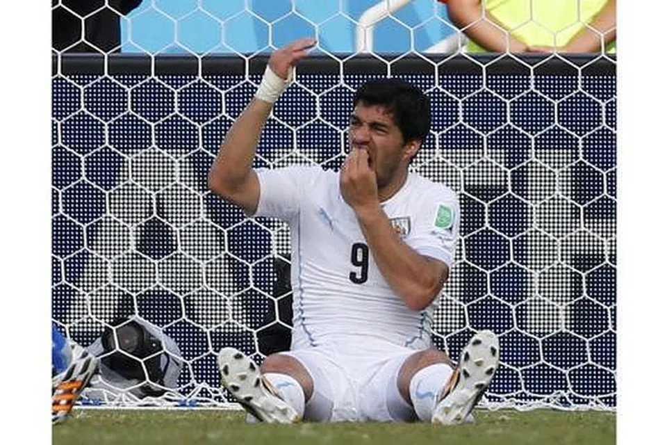 BUKAN SALAH GIGI JONGANG: Luis Suarez, dalam keadaan terduduk, memegang gigi, seolah-olah mahu membetulkan kedudukannya selepas menggigit pemain Italy, Giorgio Chiellini. - Foto REUTERS